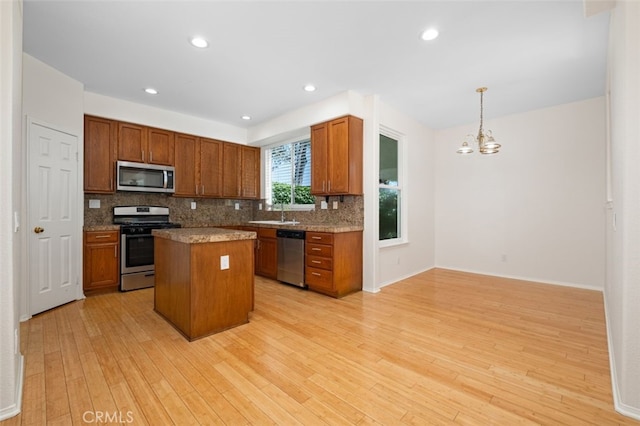 8542 E Heatherview Ln, Orange, CA 92869 - kitchen featuring appliances with stainless steel finishes, a chandelier, tasteful backsplash, light wood-style floors, and a center island