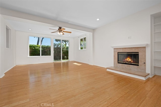 8542 E Heatherview Ln, Orange, CA 92869 - unfurnished living room with light wood-type flooring, a tile fireplace, a ceiling fan, recessed lighting, and built in features