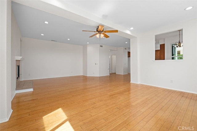 8542 E Heatherview Ln, Orange, CA 92869 - unfurnished living room featuring light wood-type flooring, a ceiling fan, a chandelier, recessed lighting, and a tiled fireplace