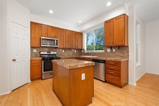 8542 E Heatherview Ln, Orange, CA 92869 - kitchen with stainless steel appliances, a sink, a center island, decorative backsplash, and light wood-style flooring