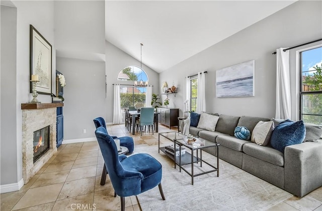4017 Cottonwood Grove Trl, Calabasas, CA 91301 - living area with light tile patterned floors, a stone fireplace, baseboards, high vaulted ceiling, and a chandelier