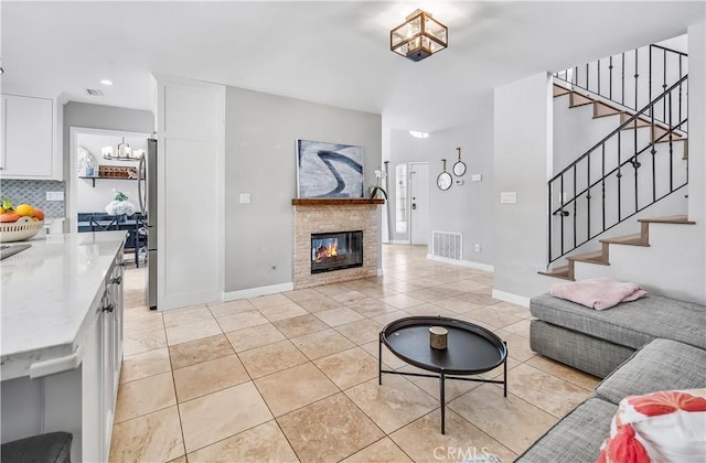 4017 Cottonwood Grove Trl, Calabasas, CA 91301 - living area with a chandelier, stairs, light tile patterned floors, a glass covered fireplace, and baseboards