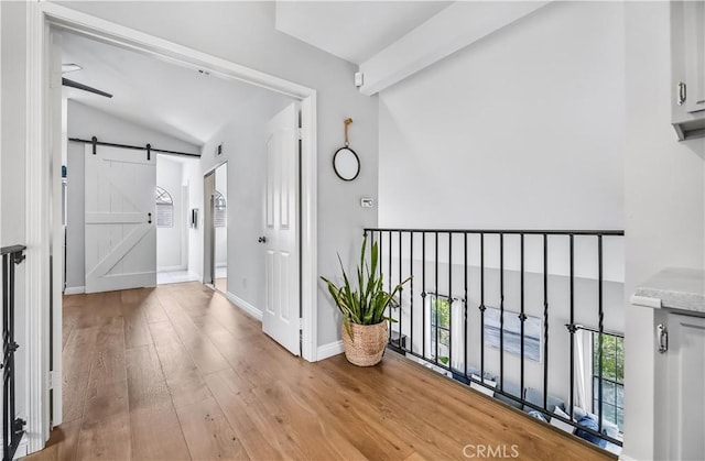 4017 Cottonwood Grove Trl, Calabasas, CA 91301 - hall with vaulted ceiling, a barn door, light wood-style floors, and baseboards