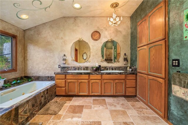 2743 Rodman Dr, Los Osos, CA 93402 - full bath with stone tile floors, a tub with jets, a chandelier, double vanity, and lofted ceiling