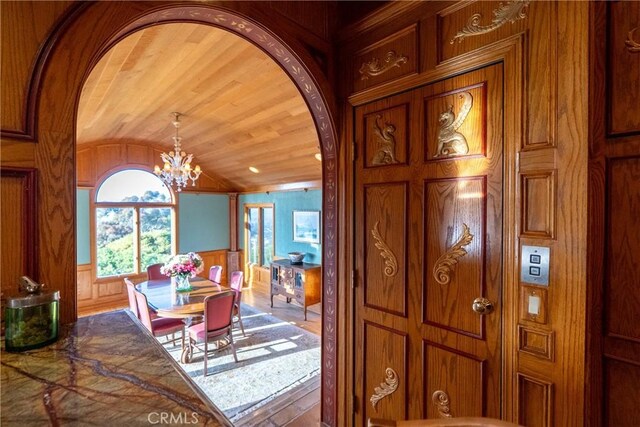 2743 Rodman Dr, Los Osos, CA 93402 - dining area featuring arched walkways, a chandelier, lofted ceiling, wood walls, and wood finished floors