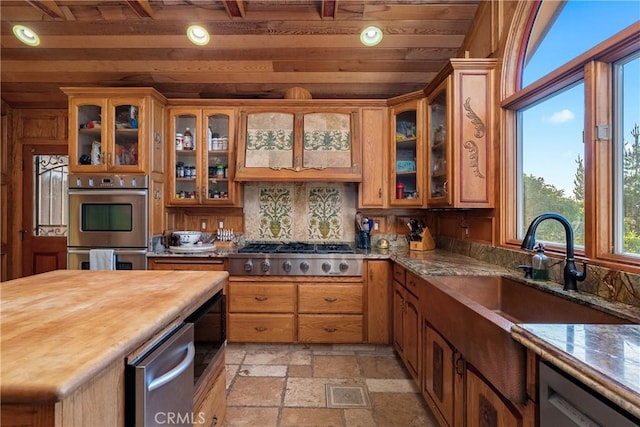 2743 Rodman Dr, Los Osos, CA 93402 - kitchen with stainless steel appliances, stone tile floors, wood ceiling, a sink, and glass insert cabinets