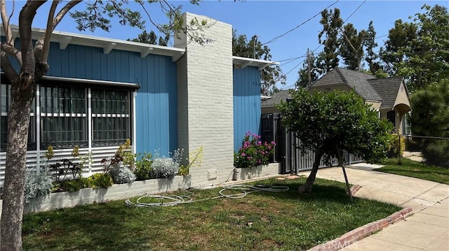 view of property exterior with a chimney, fence, and brick siding