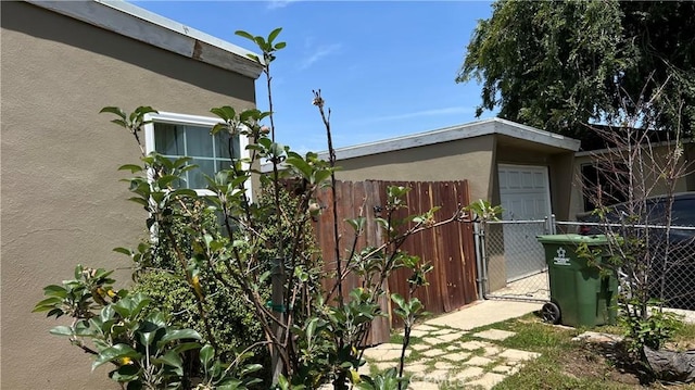 view of property exterior with stucco siding, fence, a gate, and a garage