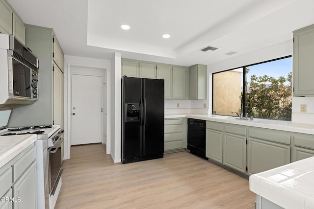 72460 Rodeo Way, Rancho Mirage, CA 92270 - kitchen featuring black appliances, tile counters, a tray ceiling, recessed lighting, and light wood-style floors