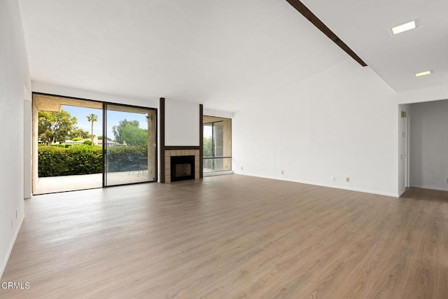 72460 Rodeo Way, Rancho Mirage, CA 92270 - unfurnished living room with plenty of natural light, light wood-type flooring, a tiled fireplace, expansive windows, and baseboards