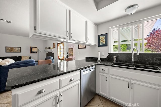 kitchen with stainless steel dishwasher, a sink, white cabinets, dark stone counters, and a peninsula