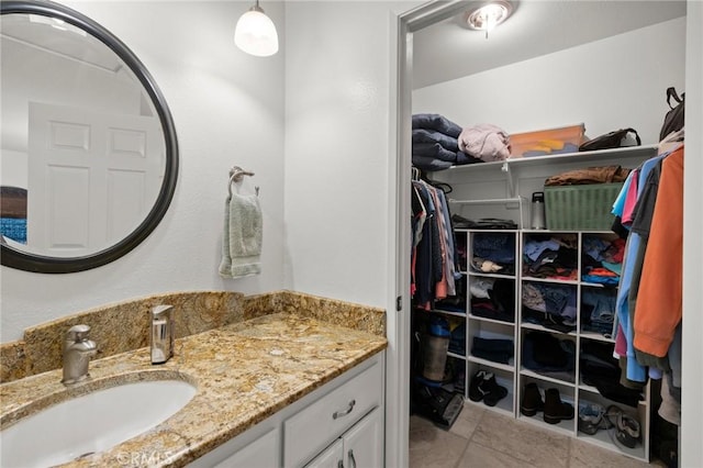 bathroom with vanity, a walk in closet, and tile patterned floors