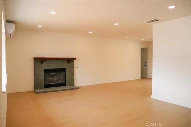 16109 Chuka Ave, Palmdale, CA 93591 - unfurnished living room with wood finished floors, recessed lighting, an AC wall unit, a glass covered fireplace, and baseboards