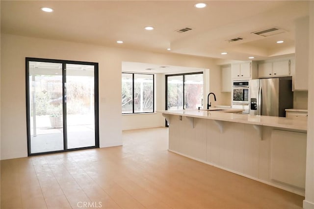 16109 Chuka Ave, Palmdale, CA 93591 - kitchen featuring stainless steel appliances, a sink, light countertops, recessed lighting, and a kitchen bar