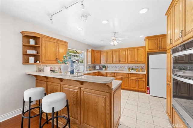 18633 Gledhill St, Northridge, CA 91324 - kitchen featuring freestanding refrigerator, double oven, a peninsula, tasteful backsplash, and a breakfast bar