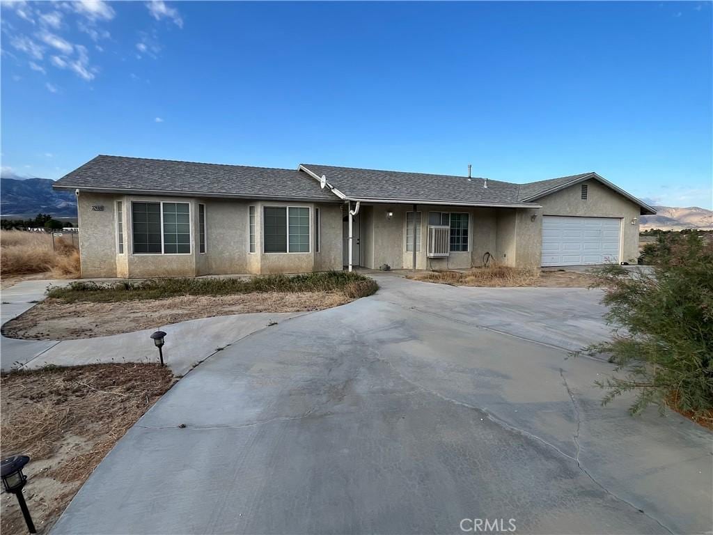 ranch-style home with stucco siding, a garage, and concrete driveway