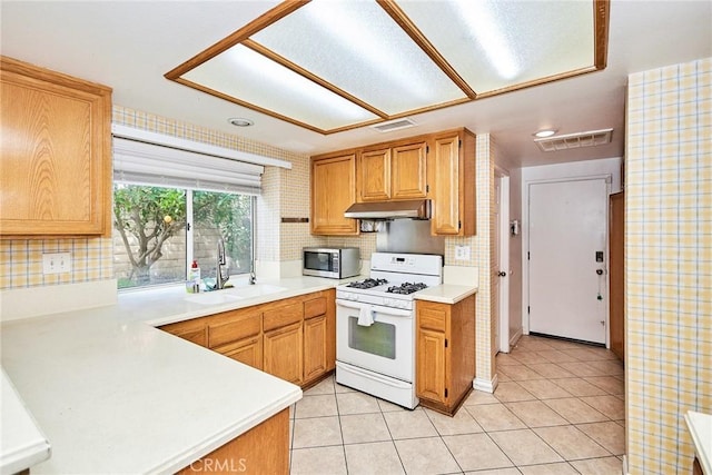 9615 Shadow Springs Dr, Moreno Valley, CA 92557 - kitchen featuring white gas range, stainless steel microwave, under cabinet range hood, a sink, and light countertops