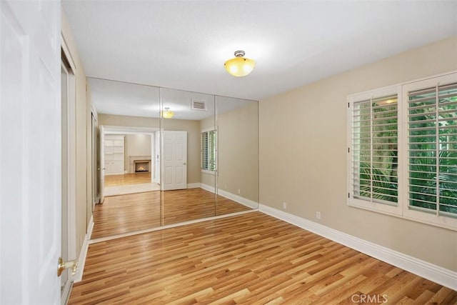 25412 Hugo Rd, Laguna Niguel, CA 92677 - unfurnished bedroom featuring light wood-style floors, a closet, and a warm lit fireplace