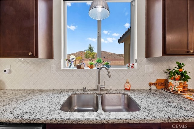36438 Geranium Dr, Lake Elsinore, CA 92532 - kitchen with a sink, light stone countertops, dark brown cabinets, decorative backsplash, and dishwasher