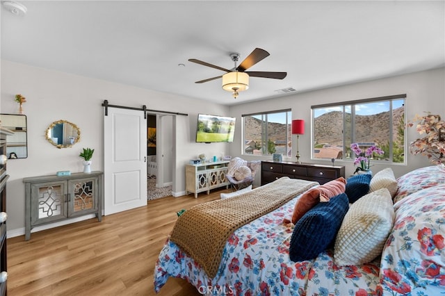 36438 Geranium Dr, Lake Elsinore, CA 92532 - bedroom with a barn door, light wood-style floors, ceiling fan, and baseboards