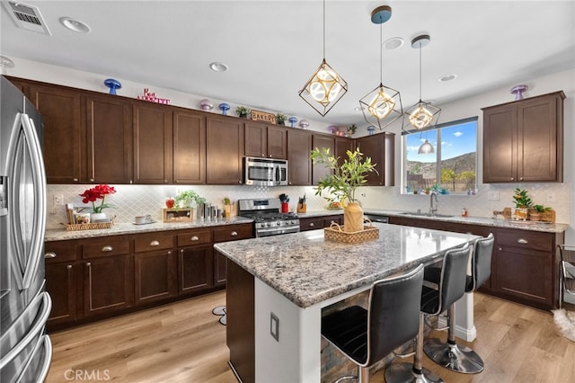 36438 Geranium Dr, Lake Elsinore, CA 92532 - kitchen featuring stainless steel appliances, a sink, light wood-style flooring, a breakfast bar area, and recessed lighting