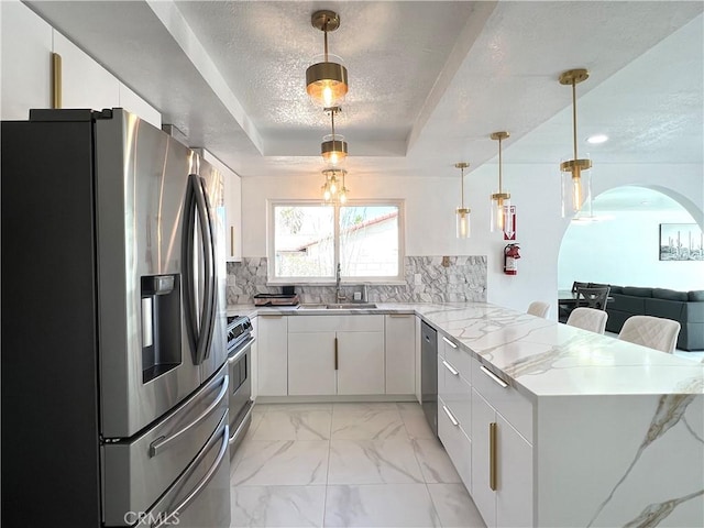 445 E San Rafael Dr, Palm Springs, CA 92262 - kitchen with stainless steel appliances, a sink, a peninsula, arched walkways, and a raised ceiling