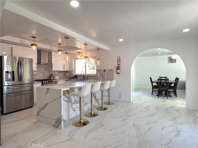 445 E San Rafael Dr, Palm Springs, CA 92262 - kitchen with stainless steel appliances, wall chimney range hood, arched walkways, a peninsula, and a breakfast bar