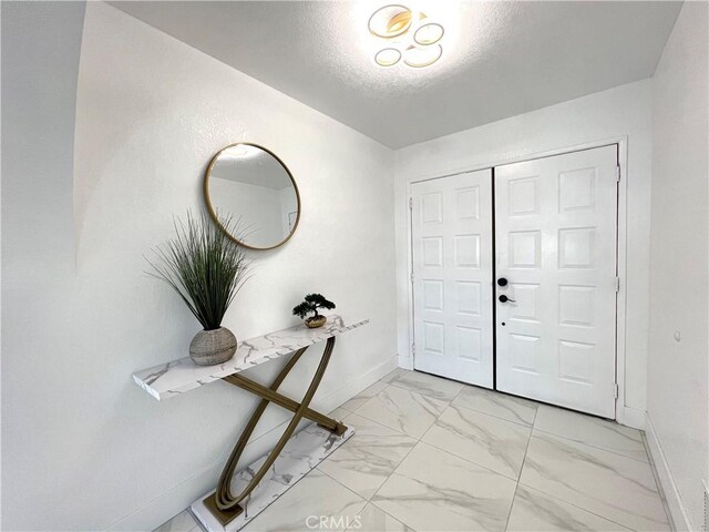 445 E San Rafael Dr, Palm Springs, CA 92262 - entrance foyer with light marble finish flooring, baseboards, and a textured ceiling