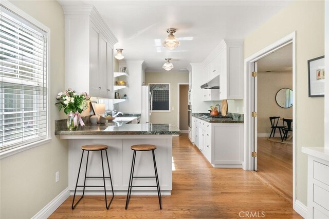 921 Arbutus Ave, Chico, CA 95926 - kitchen with ventilation hood, white cabinetry, a peninsula, and a kitchen bar