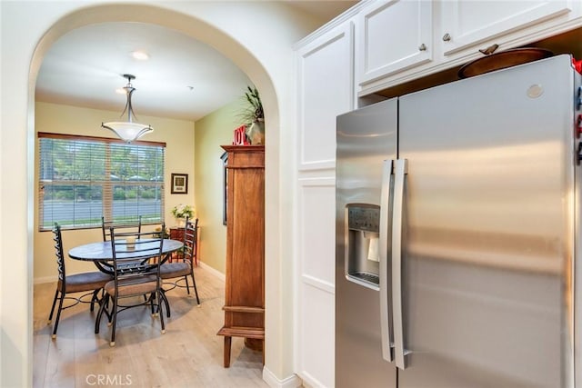 4329 Junction St Unit 103, Corona, CA 92883 - kitchen with stainless steel fridge with ice dispenser, arched walkways, baseboards, white cabinetry, and light wood-type flooring