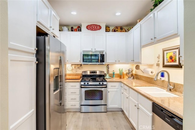 4329 Junction St Unit 103, Corona, CA 92883 - kitchen featuring appliances with stainless steel finishes, a sink, white cabinetry, light wood-style floors, and light stone counters