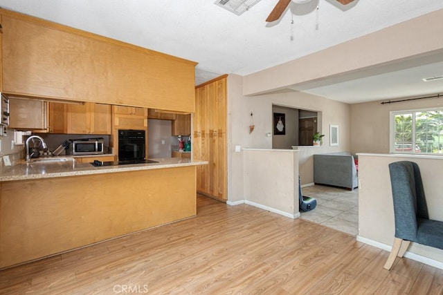 1030 Perrisito St, Perris, CA 92570 - kitchen with black appliances, a sink, light wood-type flooring, a peninsula, and a ceiling fan
