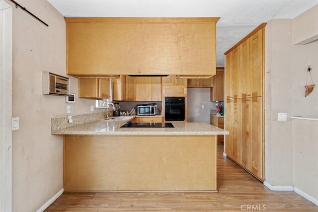 1030 Perrisito St, Perris, CA 92570 - kitchen with black appliances, light wood-style flooring, a peninsula, a sink, and baseboards