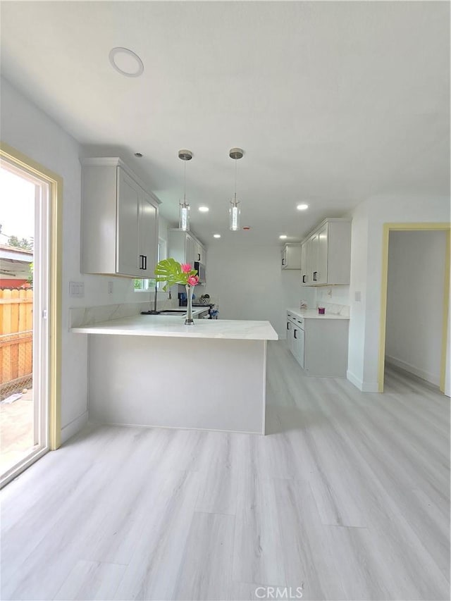 140 E Colden Ave, Los Angeles, CA 90003 - kitchen featuring a peninsula, light countertops, light wood-style flooring, decorative light fixtures, and baseboards