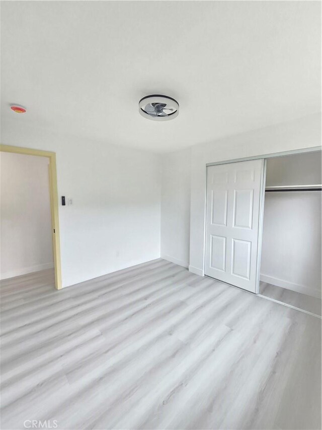 140 E Colden Ave, Los Angeles, CA 90003 - unfurnished bedroom with a closet, light wood-style floors, and baseboards