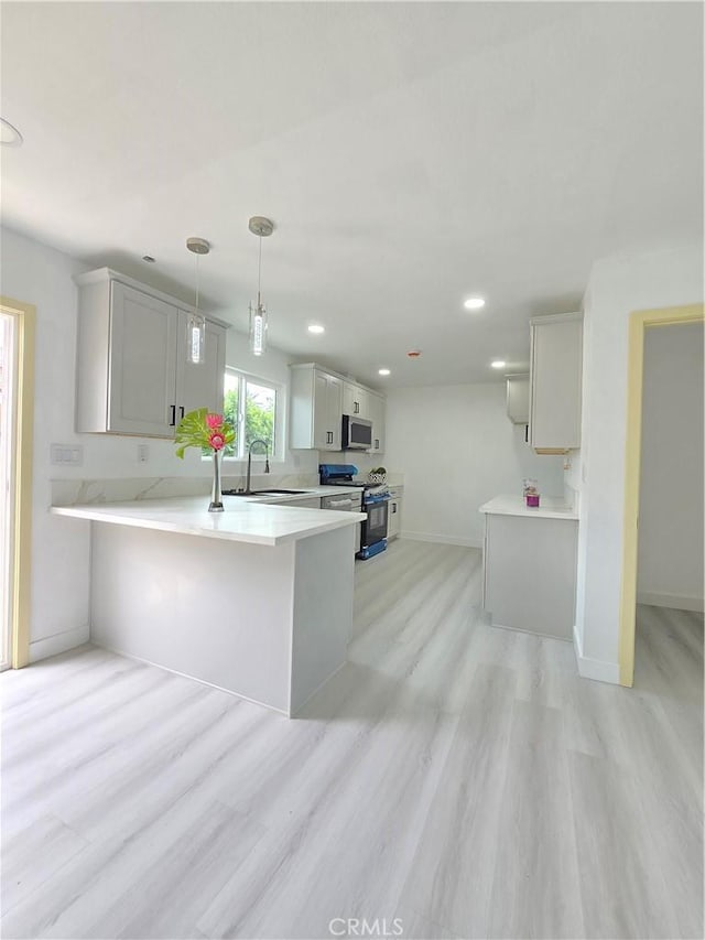 140 E Colden Ave, Los Angeles, CA 90003 - kitchen with range with gas stovetop, stainless steel microwave, a peninsula, baseboards, and light wood-style flooring