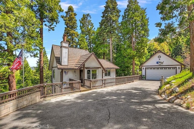 145 Cumberland Dr, Lake Arrowhead, CA 92352 - view of front of property featuring a chimney, a detached garage, a wooden deck, stucco siding, and an outbuilding