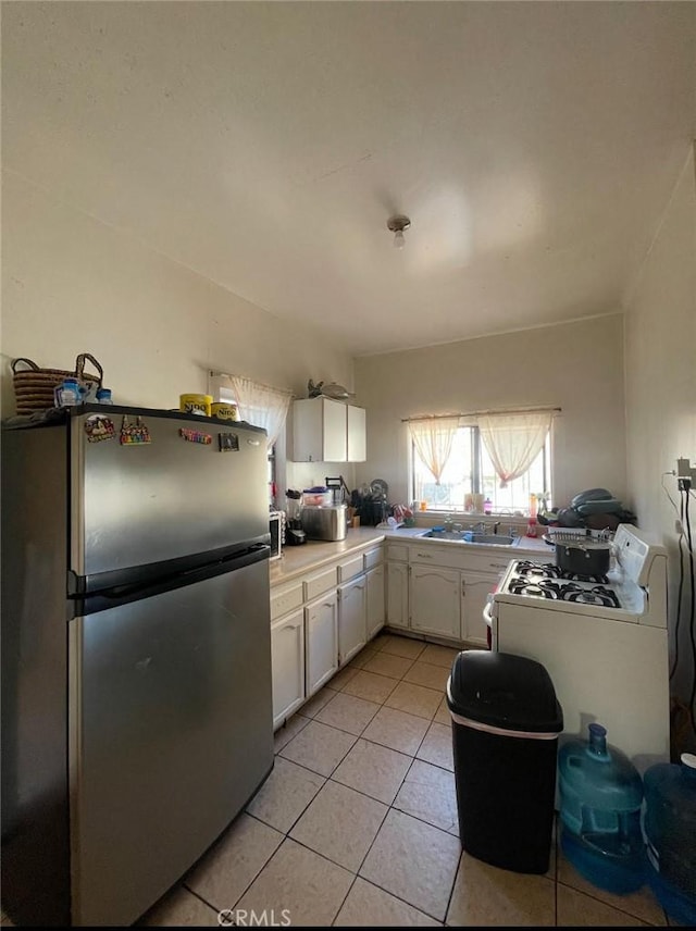 309 N Willowbrook Ave, Compton, CA 90220 - kitchen featuring freestanding refrigerator, white cabinets, light tile patterned floors, a sink, and white gas range oven