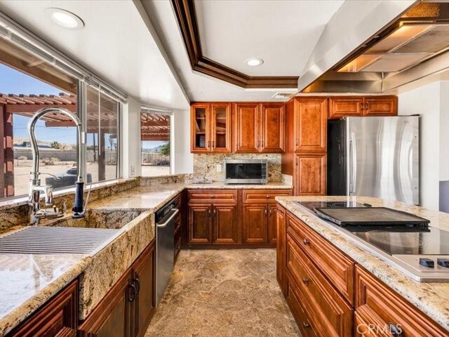 4689 Stirrup Ln Unit 29, Palms, CA 92277 - kitchen featuring stainless steel appliances, a tray ceiling, a sink, wall chimney exhaust hood, and glass insert cabinets