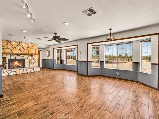 4689 Stirrup Ln Unit 29, Palms, CA 92277 - unfurnished living room featuring wood finished floors, healthy amount of natural light, a stone fireplace, a wainscoted wall, and baseboards