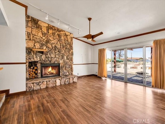 4689 Stirrup Ln Unit 29, Palms, CA 92277 - unfurnished living room featuring rail lighting, wood finished floors, baseboards, a stone fireplace, and ornamental molding