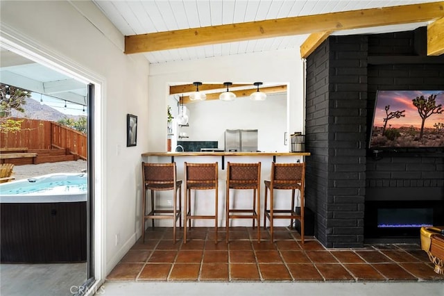 60515 Alta Loma Dr, Joshua Tree, CA 92252 - kitchen with stainless steel fridge, beamed ceiling, and a large fireplace