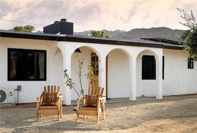 60515 Alta Loma Dr, Joshua Tree, CA 92252 - back of property with stucco siding, a cooling unit, a chimney, and a mountain view