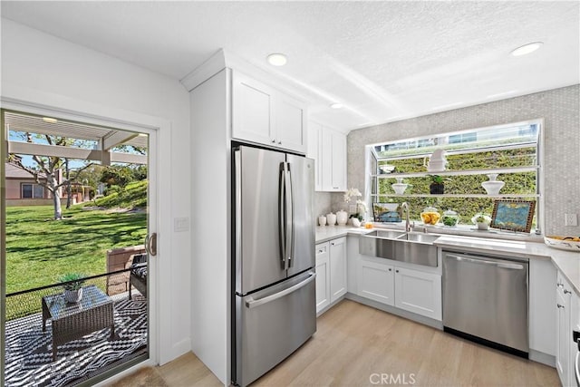 28412 Buena Vis, Mission Viejo, CA 92692 - kitchen with appliances with stainless steel finishes, a sink, light wood-style flooring, light countertops, and white cabinets