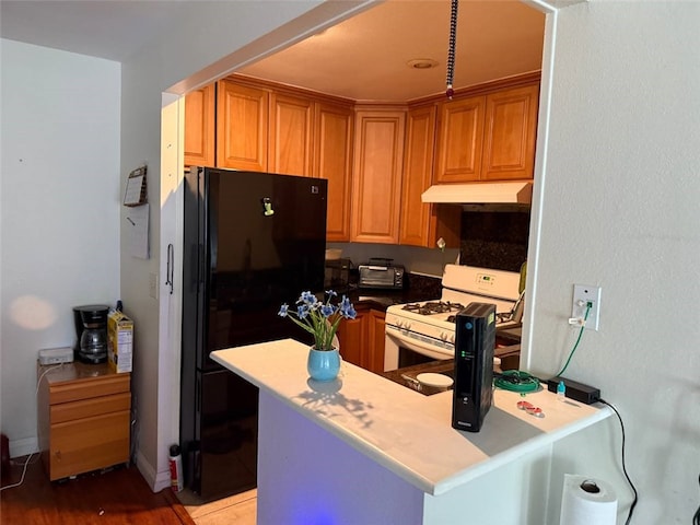 25779 Via Lomas Unit 170, Laguna Hills, CA 92653 - kitchen featuring white gas range oven, freestanding refrigerator, under cabinet range hood, light wood-style flooring, and brown cabinets