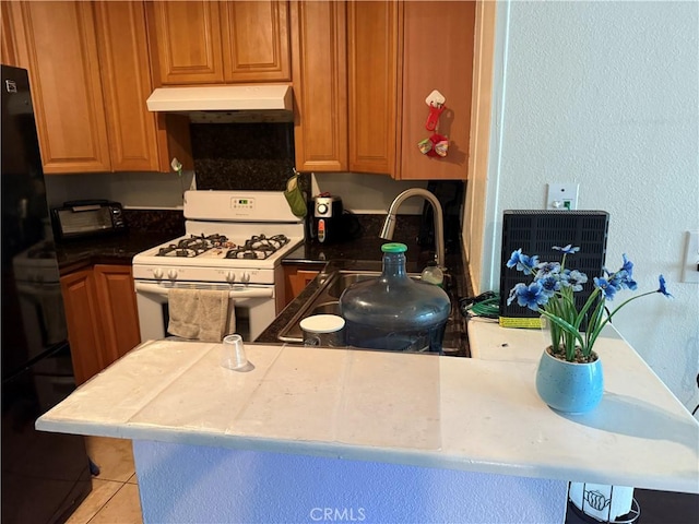 25779 Via Lomas Unit 170, Laguna Hills, CA 92653 - kitchen with white gas range oven, under cabinet range hood, freestanding refrigerator, a sink, and light tile patterned flooring