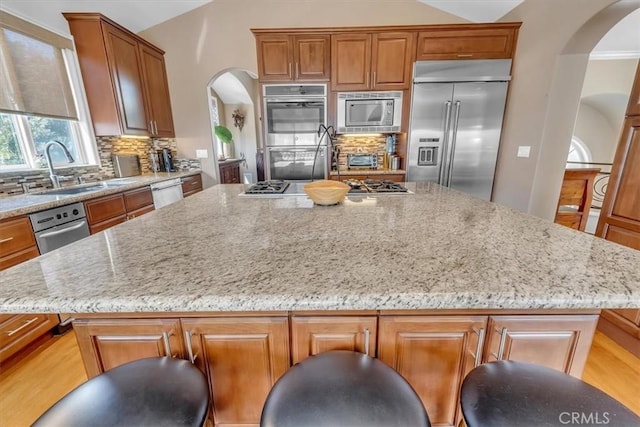 723 N Lucia Ave Unit A, Redondo Beach, CA 90277 - kitchen featuring built in appliances, arched walkways, a sink, a kitchen island, and light stone counters