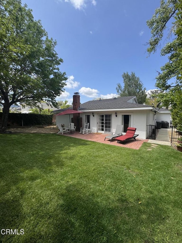 rear view of property featuring a chimney, a patio, and stucco siding