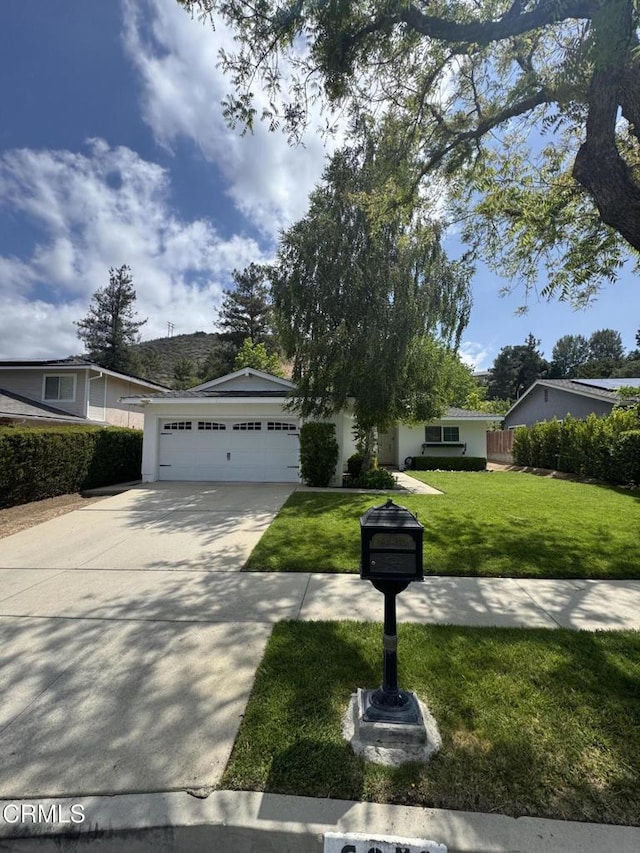 view of front facade featuring concrete driveway, a front yard, and an attached garage