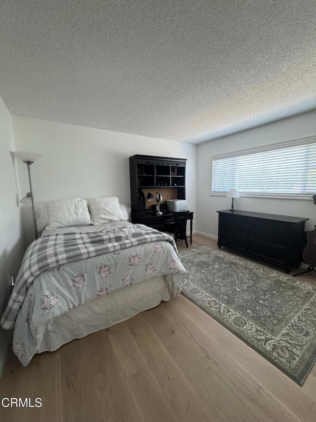 bedroom featuring wood finished floors and a textured ceiling